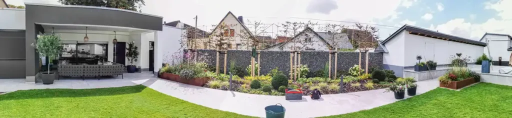 rundum Galabau GmbH – Garten mit Rasenflächen, Beeten und einem gepflasterten Gartenweg