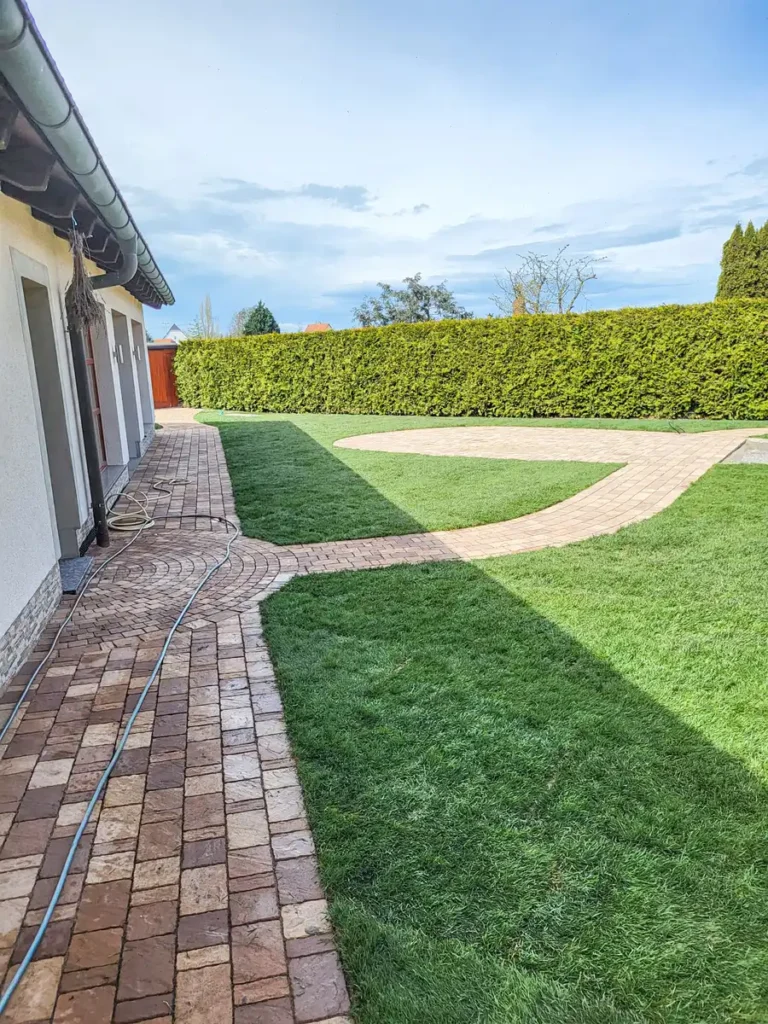 rundum Galabau GmbH – Grüne Rasenfläche mit befestigtem Gartenweg aus Naturstein, fachgerecht angelegt und gepflegt