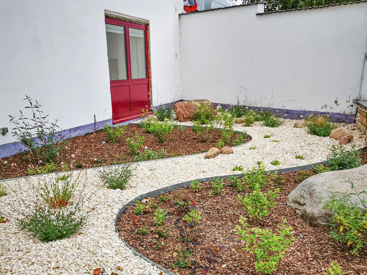 rundum Galabau GmbH – Bereich mit dekorativen Kieselsteinen und Rindenmulch